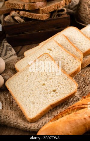 Scheiben von dunklem und weißem Brot in Box und auf Tischdecke Stockfoto