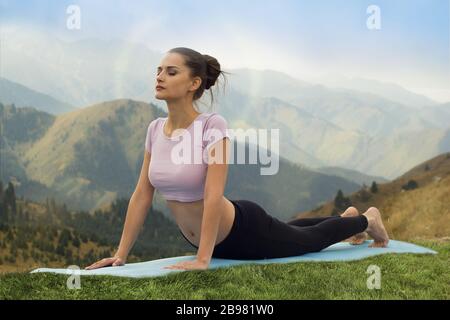 Yoga im Freien - Frau, die Yoga macht Surya Namaskar Sun Anrede Asana Urdhva Mukha Svanasana - nach oben gerichtete Hundepose in den Bergen am Morgen. Stockfoto