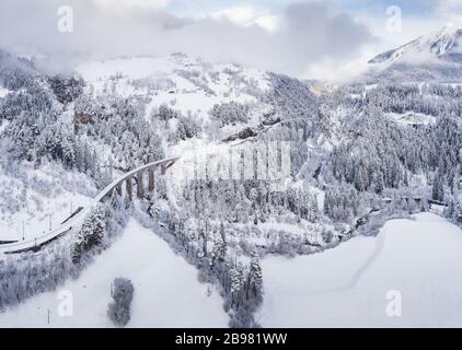 Luftbild des Landwasser-Viadukts mit Eisenbahn ohne berühmten Zug im Winter, Wahrzeichen der Schweiz, Schnee, Fluss und Berge Stockfoto