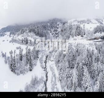 Luftbild des Landwasser-Viadukts mit Eisenbahn ohne berühmten Zug im Winter, Wahrzeichen der Schweiz, Schnee, Fluss und Berge Stockfoto