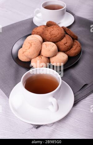 Becher mit schwarzem Tee und Keksen Stockfoto