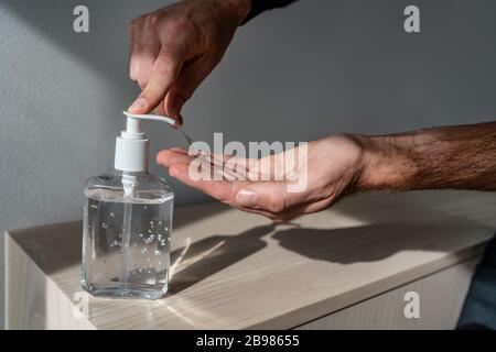 Hand Desinfektionsmittel Flasche Mann mit Spender Gel reiben für Corona Virus Hände Hygiene Coronavirus COVID-19 Pandemievorsorge Stockfoto