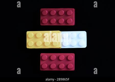 Gelbes, rotes Spielzeug mit einer weißen Paracetamol-Tablette, die die spanische Flagge auf schwarzem Grund darstellt. Konzept für Coronavirus Kovid-19-Alarmzustand, ep Stockfoto