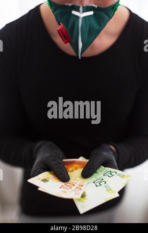 Der Mann mit schwarzen Handschuhen und einer Schutzmaske hält die israelische Währung hundertfünfzig Schekel Stockfoto