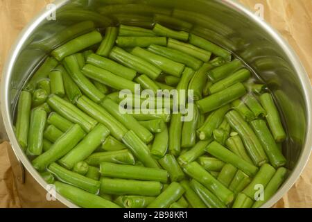 Frische rohe Bohnen in Wasser im Edelstahlkochtopf Stockfoto