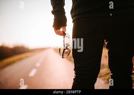 Der Biker steht auf der Straße und hält seine Brille in der Hand Stockfoto