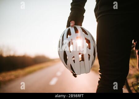 Der Radfahrer hält den Helm in der Hand und steht auf der Straße Stockfoto