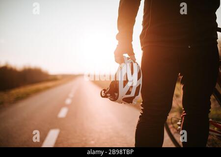 Der Radfahrer hält den Helm in der Hand und steht auf der Straße Stockfoto