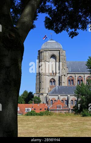 Die niederländische Flagge stolz über die spätgotischen Kirche Unserer Lieben Frau - Grote Kerk (1450-1521) in Veere, Niederlande fliegen Stockfoto