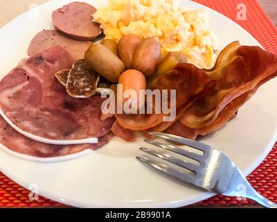 Speisen auf dem Frühstückstisch. Rührei, Omelette, Pate, Croissants, Champagner, knuspriger Speck, Würstchen. Draufsicht Stockfoto