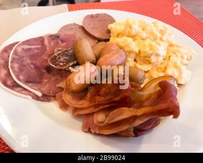 Speisen auf dem Frühstückstisch. Rührei, Omelette, Pate, Croissants, Champagner, knuspriger Speck, Würstchen. Draufsicht Stockfoto