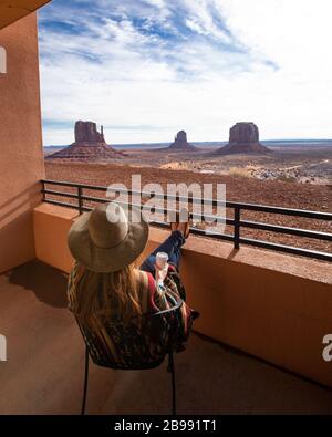 Rothaariges Mädchen mit Hut und Blick auf die Galerie vom Hotelbalkon mit Kaffee Stockfoto