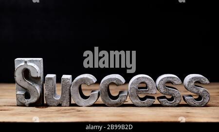 Worterfolg auf Holzhintergrund. Briefe aus Zement für erfolgreiches Konzept. Stockfoto