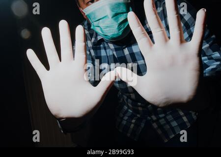 Affraid Mann Hände soziale Distanzierung mit medizinischen Handschuhen und Maske zum Schutz vor Corona-Virus Kovid-19 Stockfoto