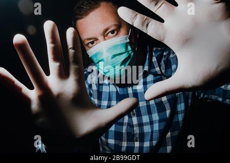 Affraid Mann Hände soziale Distanzierung mit medizinischen Handschuhen und Maske zum Schutz vor Corona-Virus Kovid-19 Stockfoto