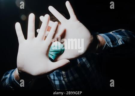 Affraid Mann Hände soziale Distanzierung mit medizinischen Handschuhen und Maske zum Schutz vor Corona-Virus Kovid-19 Stockfoto