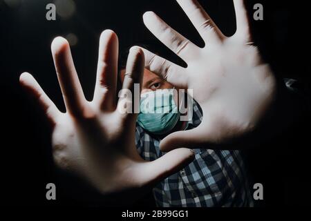 Affraid Mann Hände soziale Distanzierung mit medizinischen Handschuhen und Maske zum Schutz vor Corona-Virus Kovid-19 Stockfoto