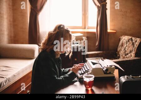 Junge weibliche Schriftstellerin, die zu Hause Schreibmaschine verwendet Stockfoto