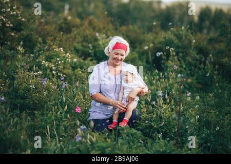 Großmutter umarmt Enkelin in der Natur im sonnigen Sommertag Stockfoto