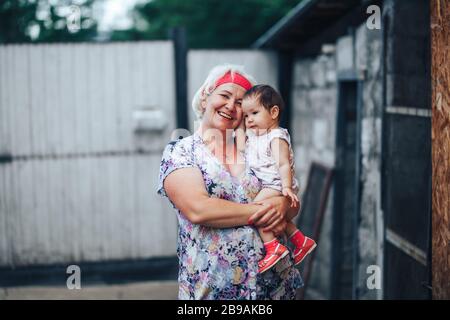Großmutter umarmt Enkelin in der Natur im sonnigen Sommertag Stockfoto