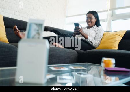 Black Woman Mit Tragbarem Wi-Fi-Drucker Zum Drucken Von Bildern Stockfoto