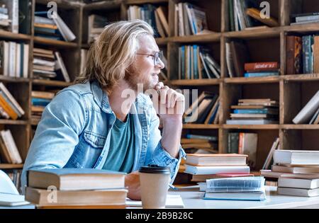 Nachdenklicher junger Student mit Kinn auf der Hand schaut weg. Stockfoto