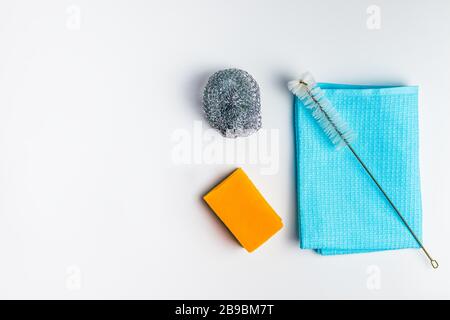 Sauberkeit und Reinigung. Blauer Lappen, orangefarbener Schwamm und Bürste auf weißem Hintergrund mit Kopierbereich Draufsicht Stockfoto