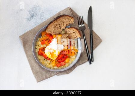 Kartoffelrisotto mit gegrilltem roten Pfeffer, pochiertem Ei und warmem Brot Stockfoto