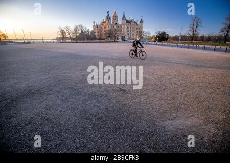 Schwerin, Deutschland. März 2020. Ein einziger Radfahrer befindet sich auf dem ansonsten menschenleeren alten Garten vor dem Schweriner Schloss im Zentrum der Landeshauptstadt. Das öffentliche Leben in Mecklenburg-Vorpommern ist im Zusammenhang mit Schutzmaßnahmen gegen die Ausbreitung des Coronavirus weiter eingeschränkt. Kredit: Jens Büttner / dpa-Zentralbild / dpa / Alamy Live News Stockfoto