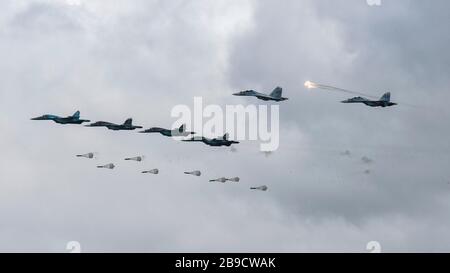 Vier Su-34-Flugzeuge bombardieren das Feld, während zwei Su-30SM Flares freisetzen. Stockfoto