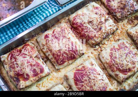 Cannelloni gefüllt mit Spinat und geröstete Paprika und verschiedenen geschmolzenen Käse in einer Aluminiumschale für Selbstbedienung oder Take-away-Mahlzeiten serviert. Stockfoto