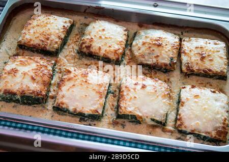 Cannelloni gefüllt mit Spinat mit verschiedenen geschmolzenen Käse in einer Aluminiumschale für Selbstbedienung oder Speisen zum Mitnehmen in Portionen serviert. Stockfoto