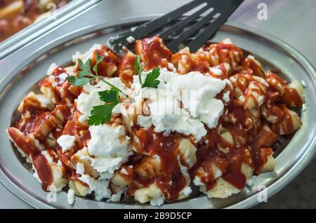 Patatas Bravas mit Knoblauch weiß Öl und heiße Soße. Rufen Sie Kartoffeln mutig. Mit einem Blatt Petersilie garniert. In einer Aluminiumschale mit einer Palette von Schwarz Stockfoto