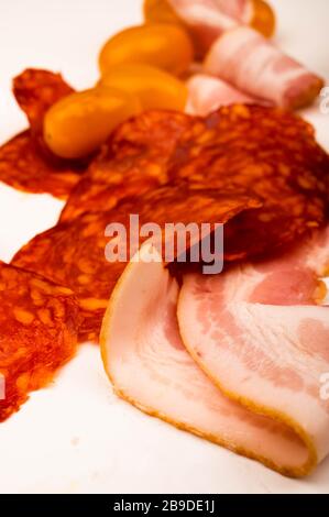 Speck und Wurst und Tomaten in Scheiben auf weißem Hintergrund. Nahaufnahme Stockfoto