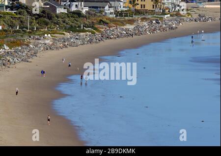 Los Angeles, Kalifornien, USA. März 2020. Strandbesucher gehen am Montag, 23. März 2020, am Strand von Zuma entlang. Der Bürgermeister von Los Angeles, Eric Garcetti, schloss Sport und Erholung in den Stadtparks von L.A. und schloss die Parkplätze an den Stränden der Stadt, nachdem zu viele Menschen in unmittelbarer Nähe zu Stränden, Pfaden und Parks gesehen hatten. Garrett bat die Bewohner, zu Hause zu bleiben und Leben zu retten. Soziale Distanzierung fordert, dass Menschen mindestens sechs Meter voneinander entfernt bleiben. Credit: UPI/Alamy Live News Stockfoto