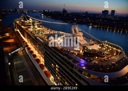 Foto von oben von einem am Kai der Holland-Amerika-kade in Rotterdam angedockten Cruiseschip nachts mit dem Euromast in der Ferne Stockfoto