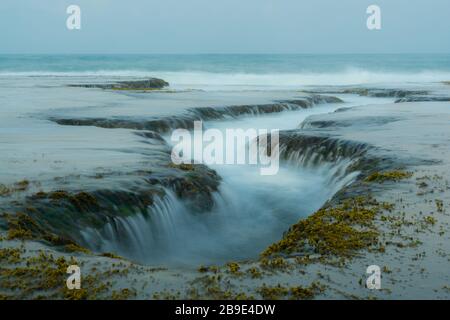 Einzigartiges Meereswasser strömt durch Felsen wie ein Wasserfall. Perfekte Lage für Fotografen in der Nähe von Sawarna, Provinz Banten, Java, Indonesien Stockfoto