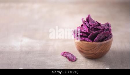 Getrocknete Scheiben von rosafarbenen Drachenfrüchten, Pitaya in Holzschale auf strukturiertem Holzhintergrund. Kopierbereich. Superfood, veganes, vegetarisches Speisekonzept. Makro von Stockfoto