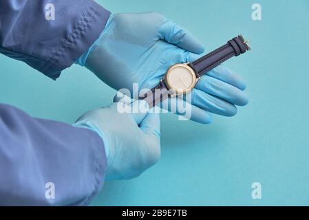 Der Arzt in Gummihandschuhen hält eine Uhr, das Konzept der Zeitpflege Stockfoto