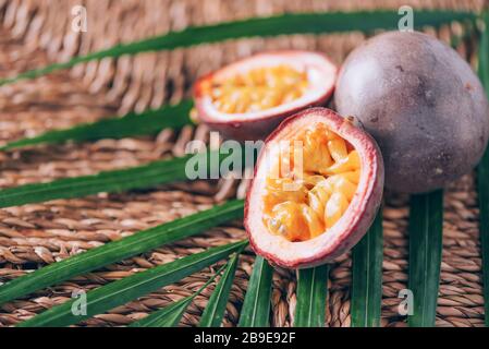 Gelbe Maracuya mit Palmblättern auf Rattanhintergrund. Kopierbereich. Passionsfrucht. Banner für kreatives Design. Sommerzeit. Tropische Reise, exotische Früchte. Stockfoto