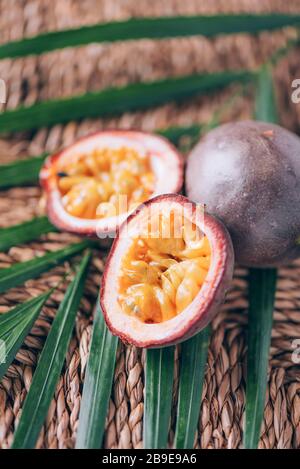 Gelbe Maracuya mit Palmblättern auf Rattanhintergrund. Kopierbereich. Passionsfrucht. Banner für kreatives Design. Sommerzeit. Tropische Reise, exotische Früchte. Stockfoto