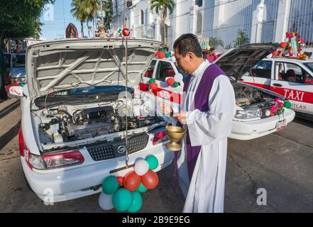 Priest Seeging schmückte vor der Prozession Taxis und Fahrer, Festival of Our Lady of Guadalupe, Straße in Catemaco, Veracruz State, Mexiko Stockfoto