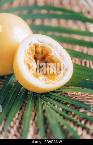 Gelbe Maracuya mit Palmblättern auf Rattanhintergrund. Kopierbereich. Passionsfrucht. Banner für kreatives Design. Sommerzeit. Tropische Reise, exotische Früchte. Stockfoto
