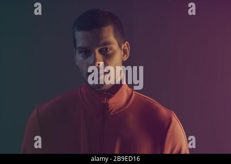 Nahaufnahme des attraktiven männlichen Modells. Retro-Wave-Porträt eines jungen Mannes im Studio. High Fashion Männermodell in bunten, hellen Neonlichtern Stockfoto