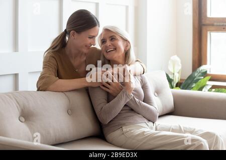 Liebevolle Erwachsene Tochter umarmt ältere Mutter und genießt einen zärtlichen Moment Stockfoto