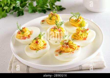 Gefüllte Eier mit Eigelb, Speck, Senf und Dill verschlingen, Nahansicht Stockfoto