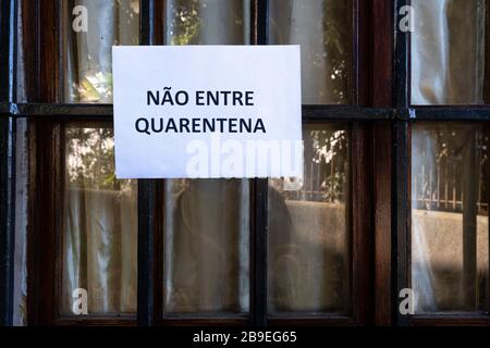 Ein Schild mit der Aufschrift "nicht eingeben", "Quarantäne in Portugiesisch", das an ein Fenster angehängt ist Stockfoto