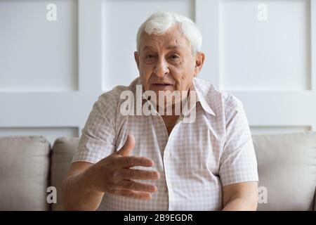 Kopf hat einen ernsthaften älteren Mann erschossen, der die Kamera betrachtet und spricht Stockfoto