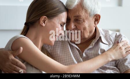 Liebevolle Erwachsene Tochter und älterer Vater berühren die Stirn und umarmen sich Stockfoto