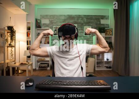 POV des professionellen Spielers, der seinen Muskel beugt, der seinen Sieg im Online-Shooter-Spiel feiert. Stockfoto